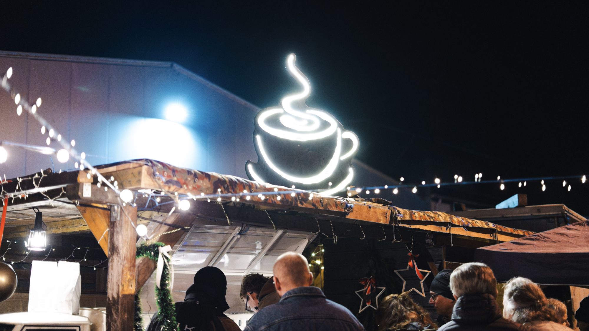 Leuchtende Kaffeetasse über dem geschmückten Stand der Coffee-Ape mit Gästen